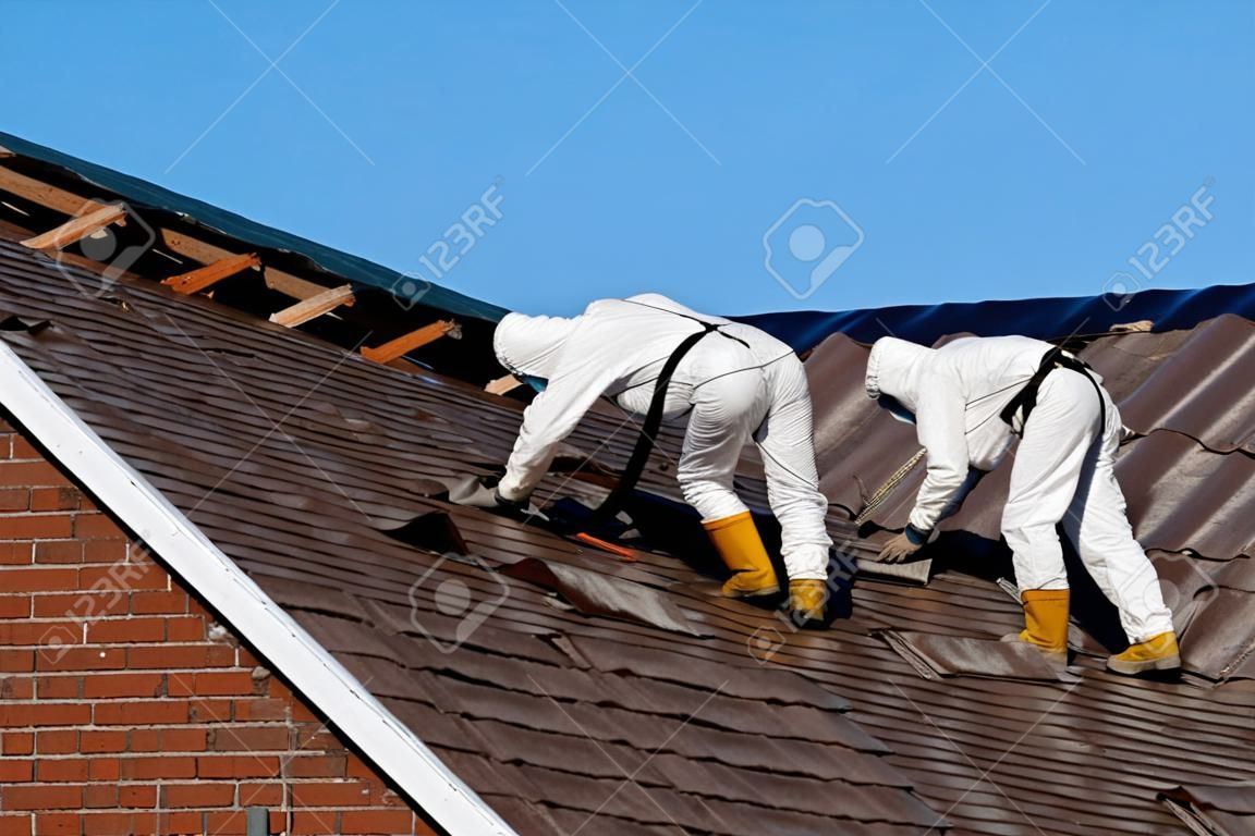 Specjaliści w kombinezonach ochronnych usuwają azbestowo-cementowe pokrycie dachowe