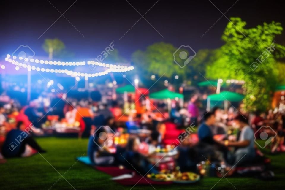 blur people picnic in a public Park with family or friends. the food festival at night