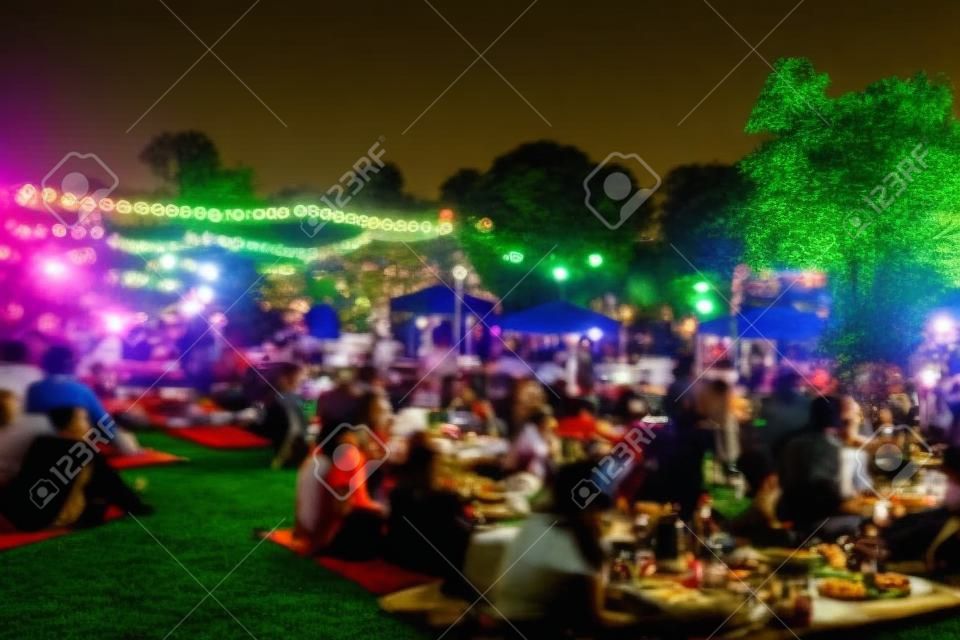 blur people picnic in a public Park with family or friends. the food festival at night