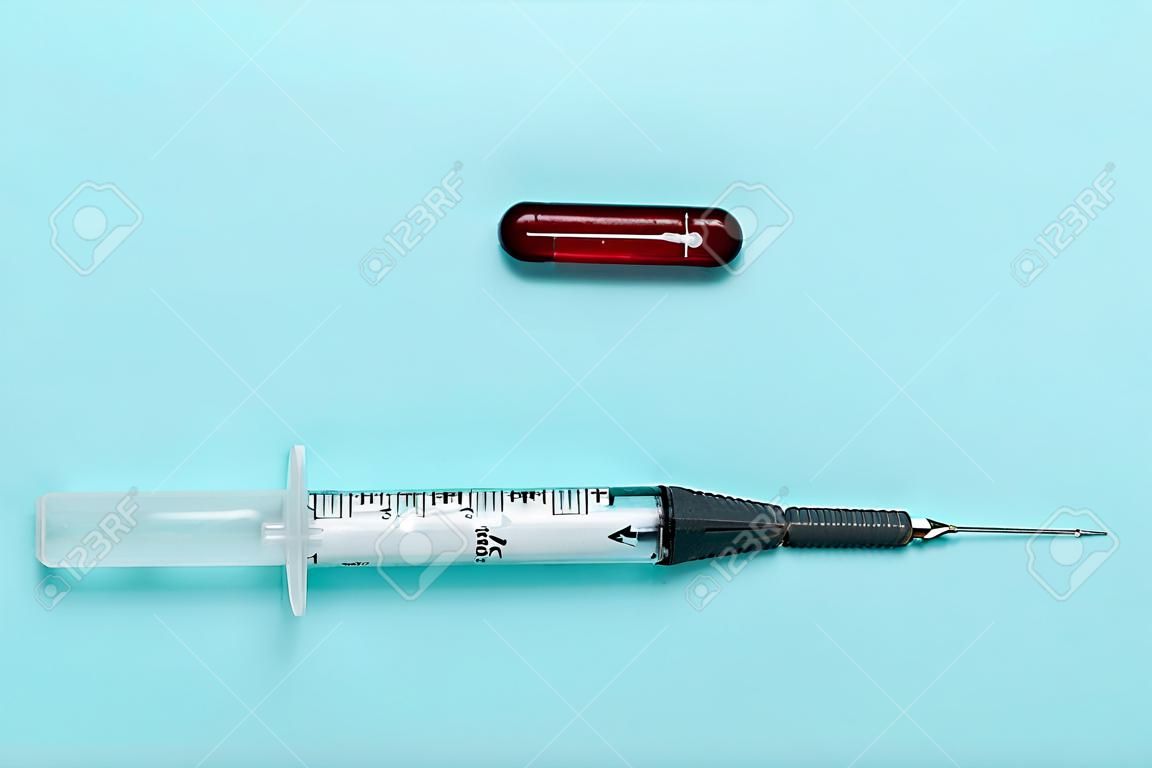 Pills and and syringe on blue background