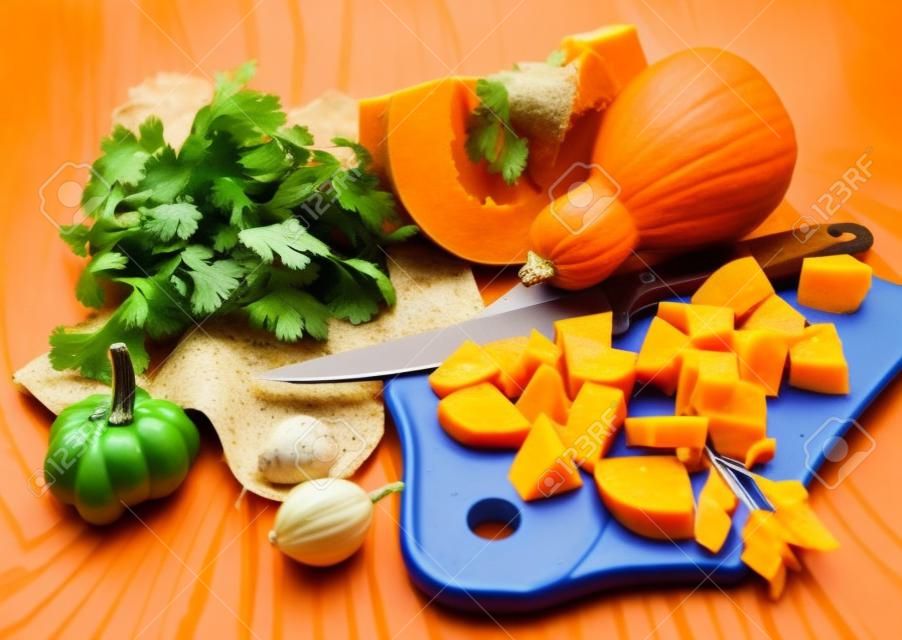 Cutting a pumpkin and vegetables ingredients for soup
