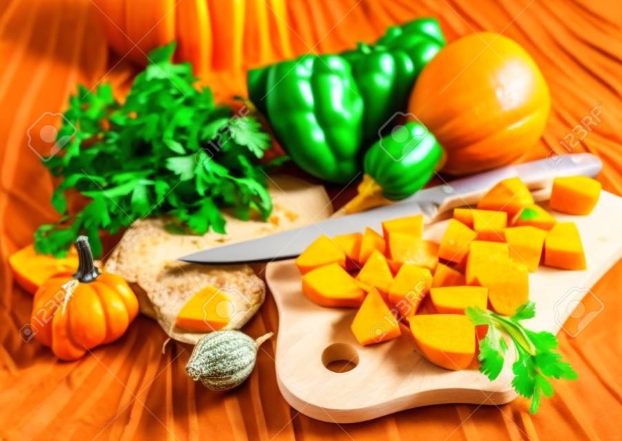 Cutting a pumpkin and vegetables ingredients for soup
