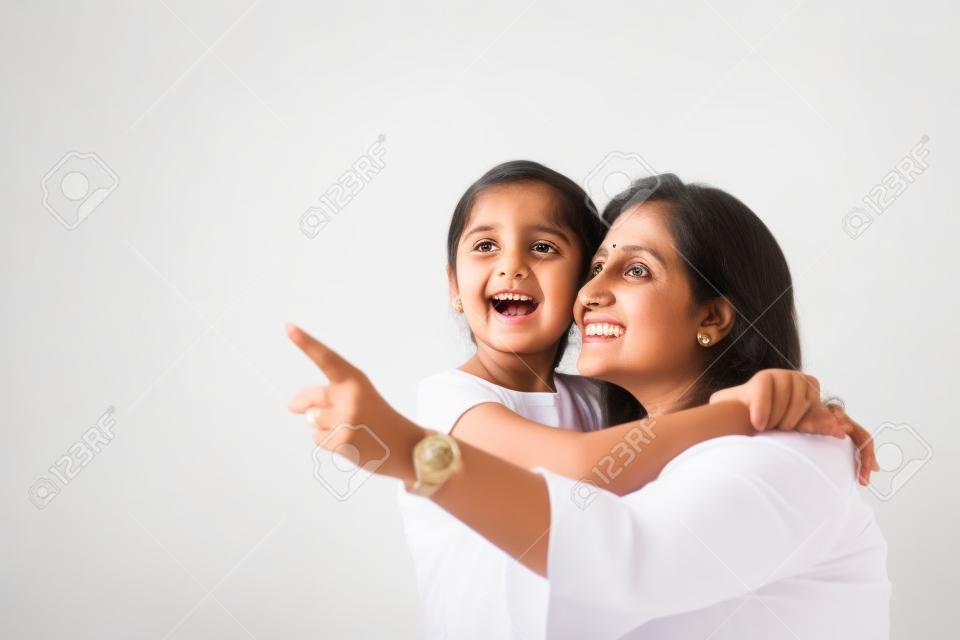 Indische Mutter Tochter auf weißem Hintergrund umarmt, küssen, reiten, fliegen, zeigen, präsentieren auf weißem Hintergrund