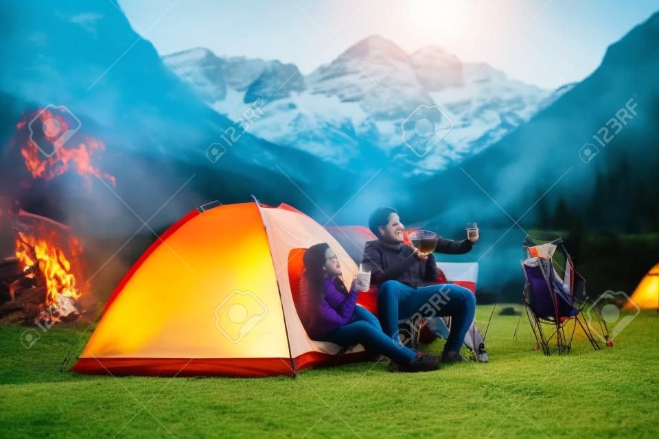 Gelukkige jonge Aziatische indianen paar camping, zittend bij tent op camping ontspannen en thee drinken.