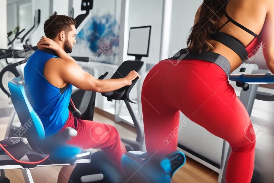 A picture from another angle where girls back is seen. Also there is her boyfriend working hard on the exercise bike as well.