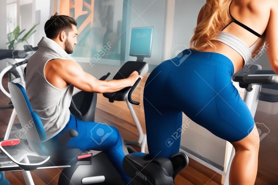 A picture from another angle where girls back is seen. Also there is her boyfriend working hard on the exercise bike as well.
