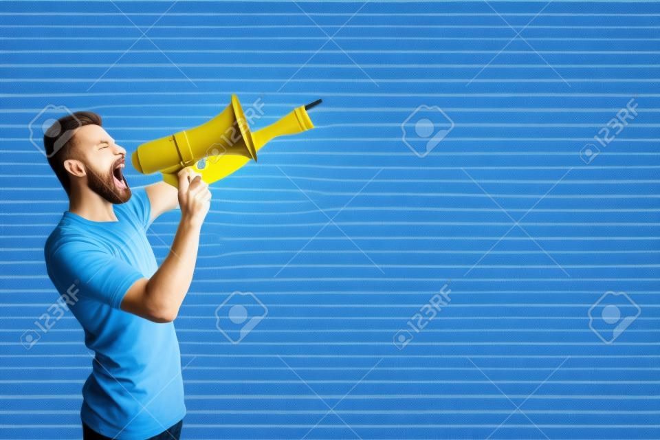 A picture of man standing and pointing forward. He is talking and screaming into megaphone. Isolated on striped and blue background.