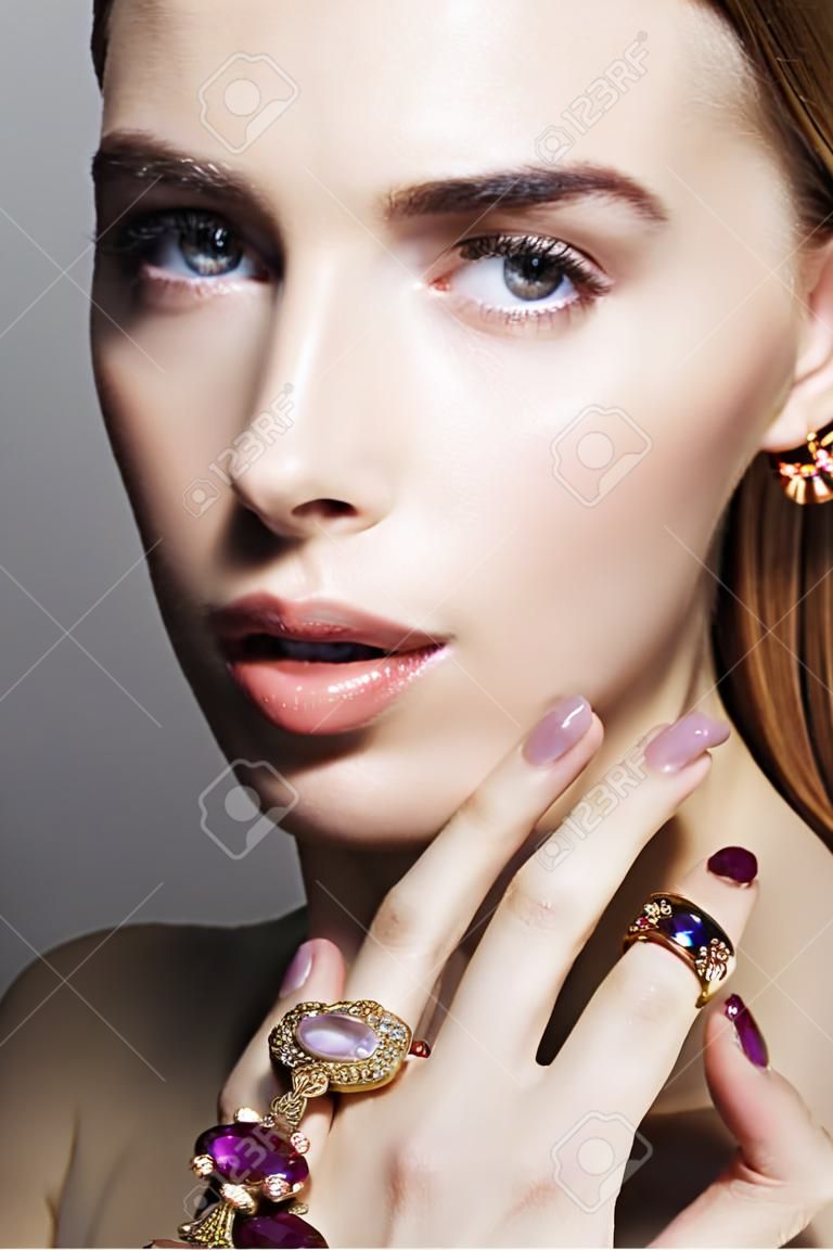Gouden sieraden op mooie meisje. jonge blonde vrouw met make-up en juwelen accessoires.