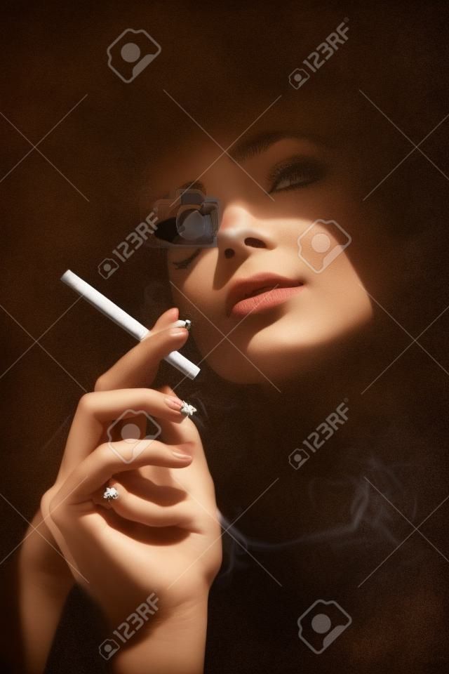 Belle femme avec une cigarette. Portrait de style rétro. Dame fille avec le visage sous l'ombre