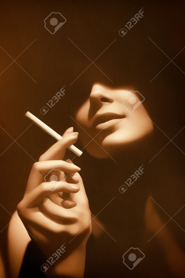 Belle femme avec une cigarette. Portrait de style rétro. Dame fille avec le visage sous l'ombre