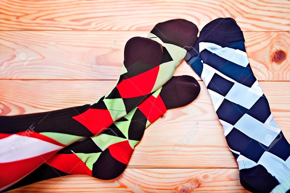 Two legs in different motley socks on a wooden floor. Top view