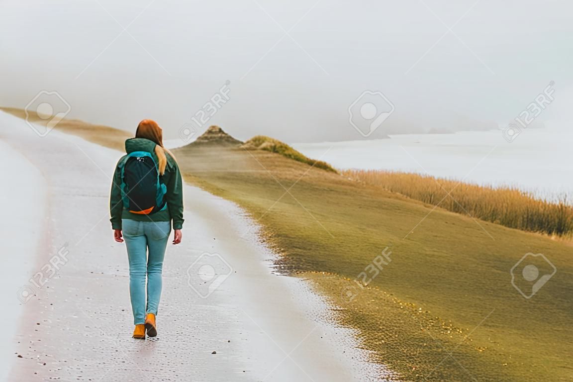 Tourist woman walking alone outdoor Travel Lifestyle wanderlust concept foggy nature adventure active vacations