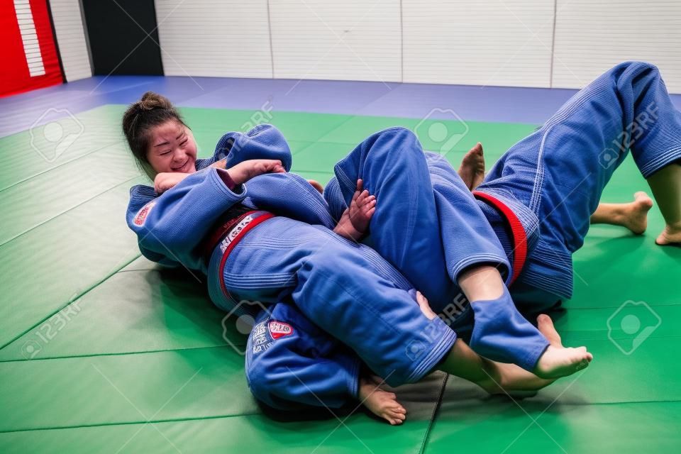 두 명의 여성이 다다미에서 싸우고 있습니다. 유도, Jiu Jitsu.