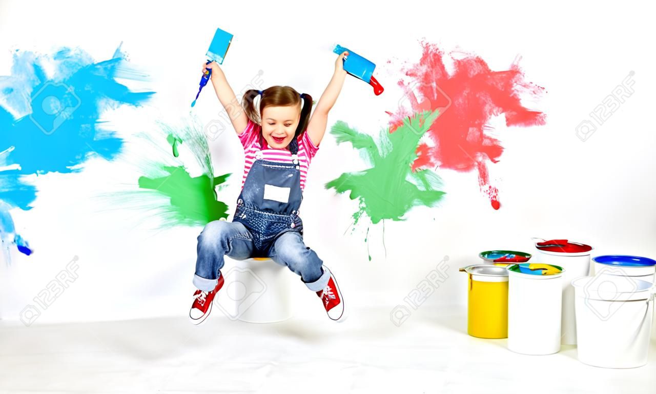 menina de criança engraçada feliz fazendo reparos, pulando e pintando a parede em casa