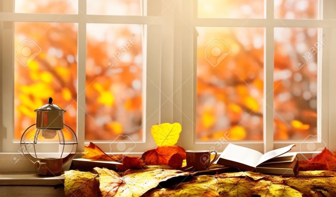 秋。秋と居心地の良い窓辺の葉、本、お茶のマグ