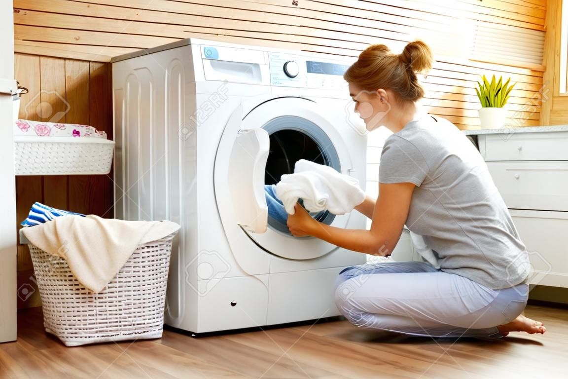 一个幸福的家庭主妇在洗衣机的洗衣房里的女人