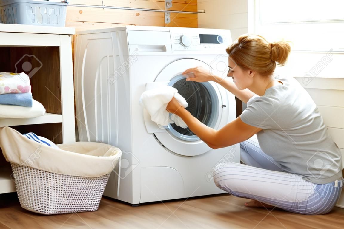 一个幸福的家庭主妇在洗衣机的洗衣房里的女人