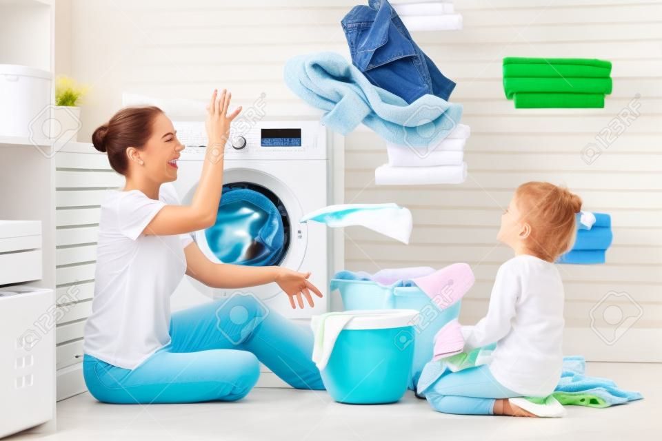 Счастливая семья, мать-домохозяйка и дочь ребенка в прачечной со стиральной машиной