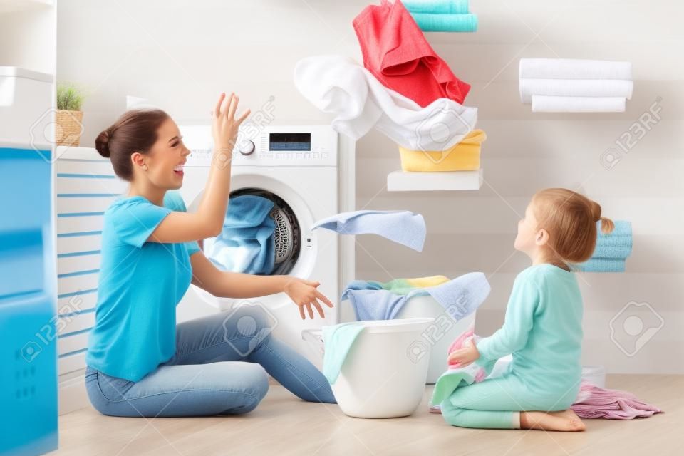 Счастливая семья, мать-домохозяйка и дочь ребенка в прачечной со стиральной машиной