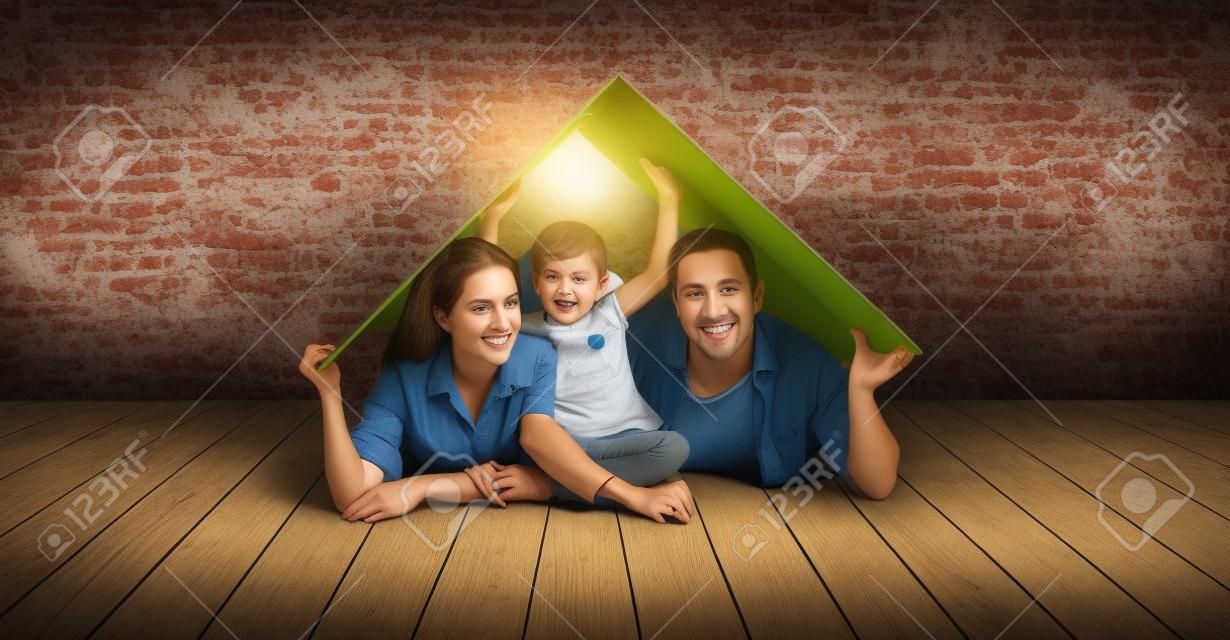 koncepcja mieszkania młodej rodziny. Matka, ojciec i dziecko w nowym domu z dachem przy pustym murem