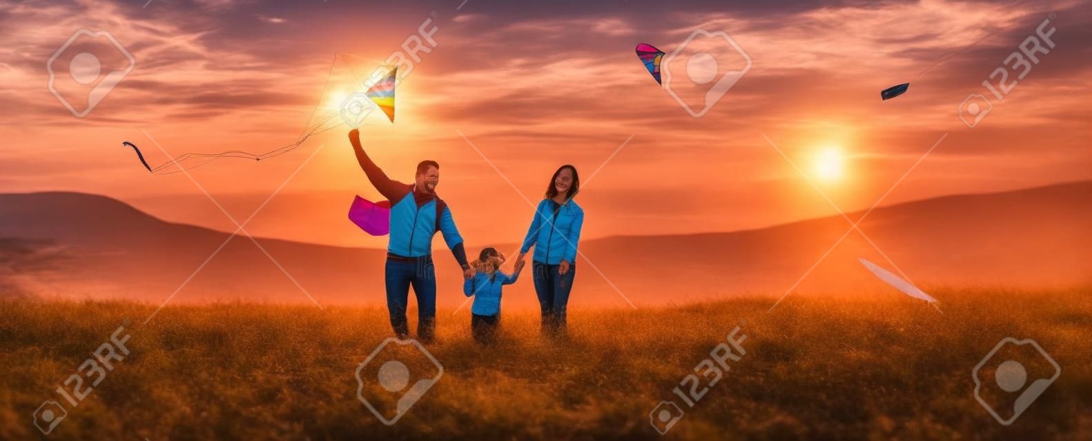 Boldog családi apa, anya és gyermeke lánya sárkányt indít a természetre naplementekor