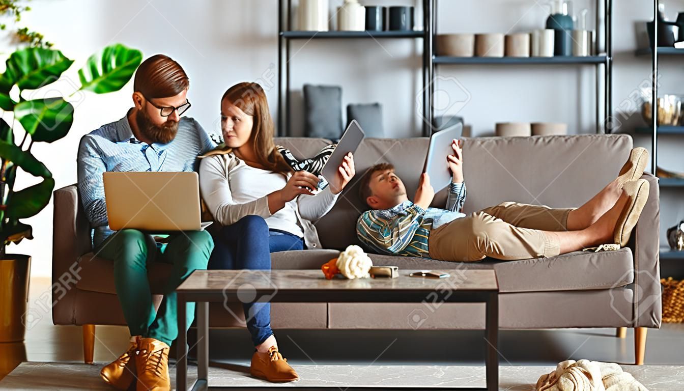 glückliches familienpaar, das sich zu hause mit laptop und tablet entspannt