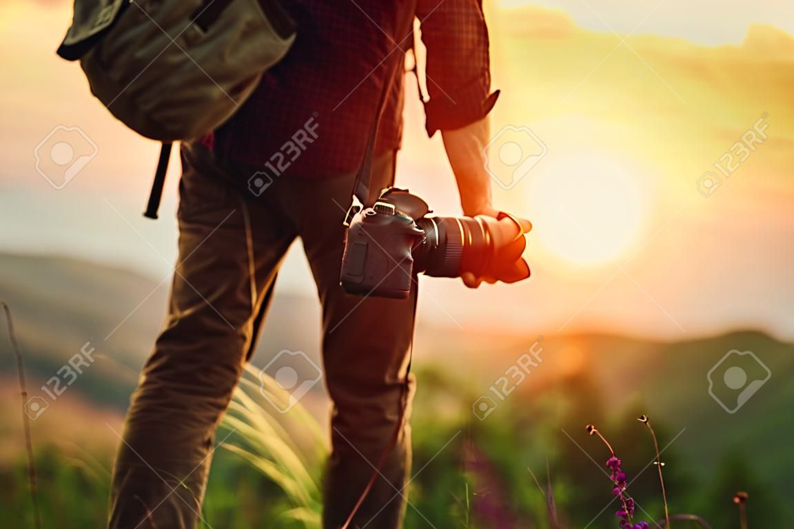 fotógrafo de viajes. Hombre viajero con cámara en las montañas al atardecer en la naturaleza