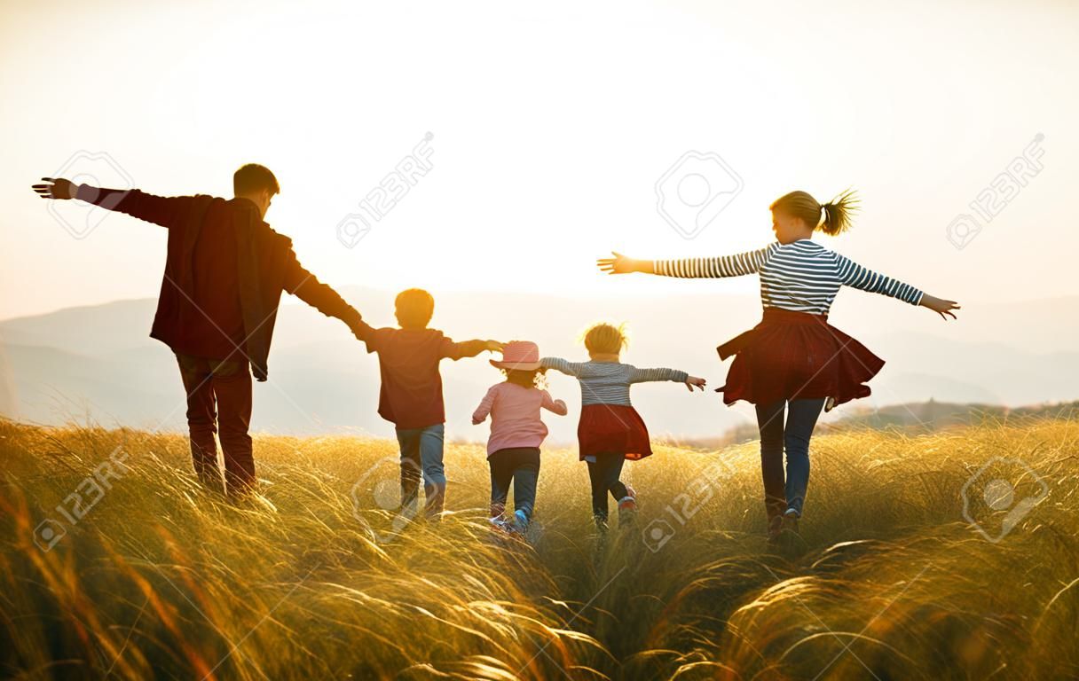 Famille heureuse : mère, père, fils et fille d'enfants sur la nature au coucher du soleil