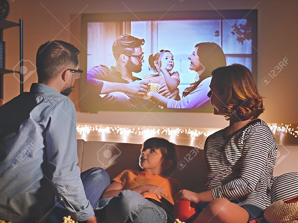 familie moeder vader en kinderen kijken projector, TV, films met popcorn in de avond thuis