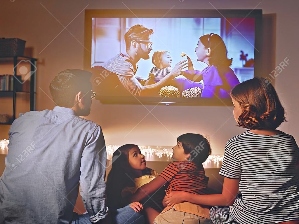 Familie Mutter Vater und Kinder schauen Projektor, Fernsehen, Filme mit Popcorn am Abend zu Hause pop