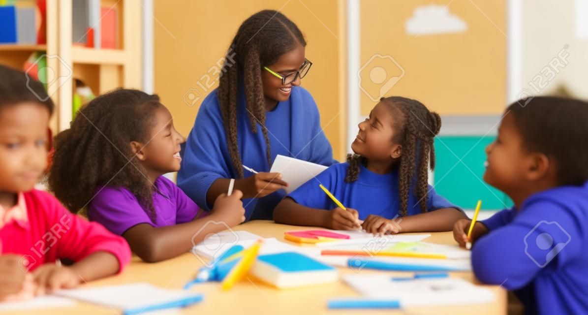 Teacher helping children with schoolwork at school