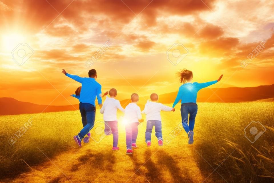 Happy large family: mother, father, children son and daughters running on nature on sunset