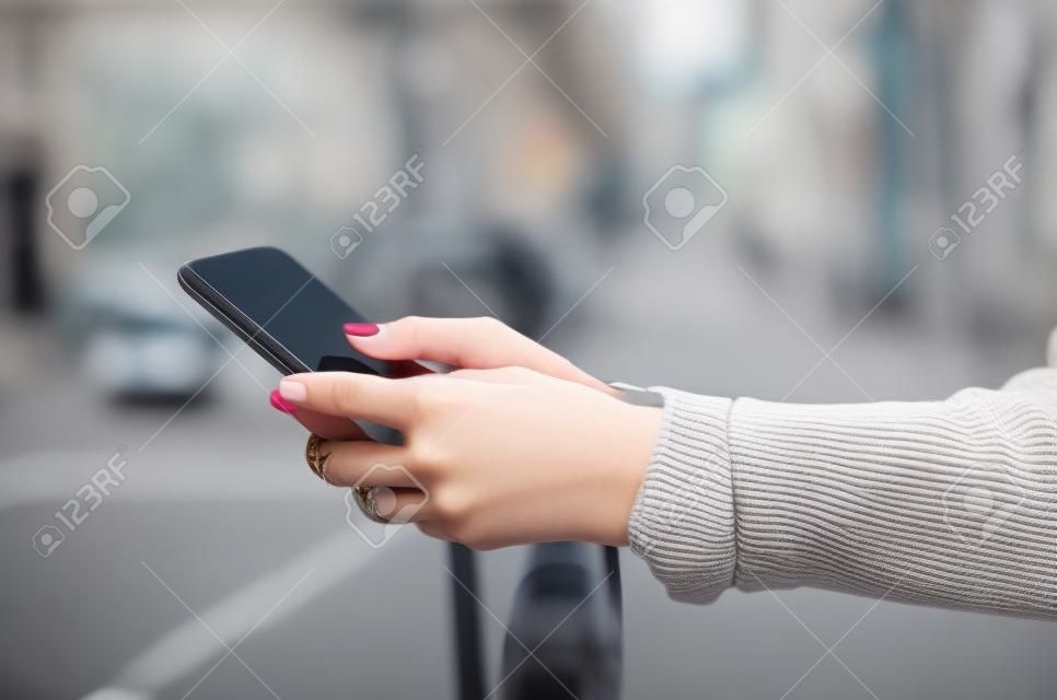 Young woman sweater in hand smartphone mobile phone in the street