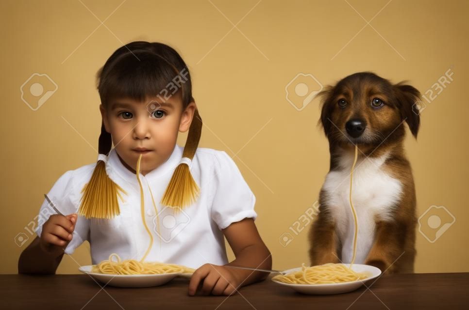 Dziecko, dzieciak, z psem jedzącym makaron siedzi przy stole na białym tle