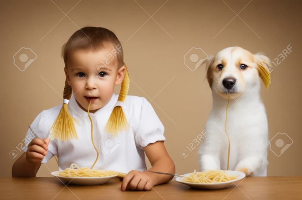 Dziecko, dzieciak, z psem jedzącym makaron siedzi przy stole na białym tle