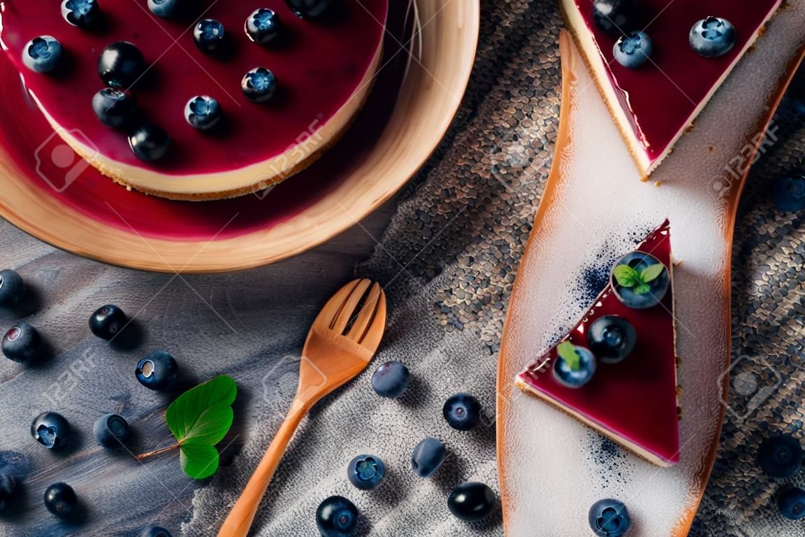 Sweet creamy blueberry cheesecake with fresh blue berries on a blue wooden background.top view.