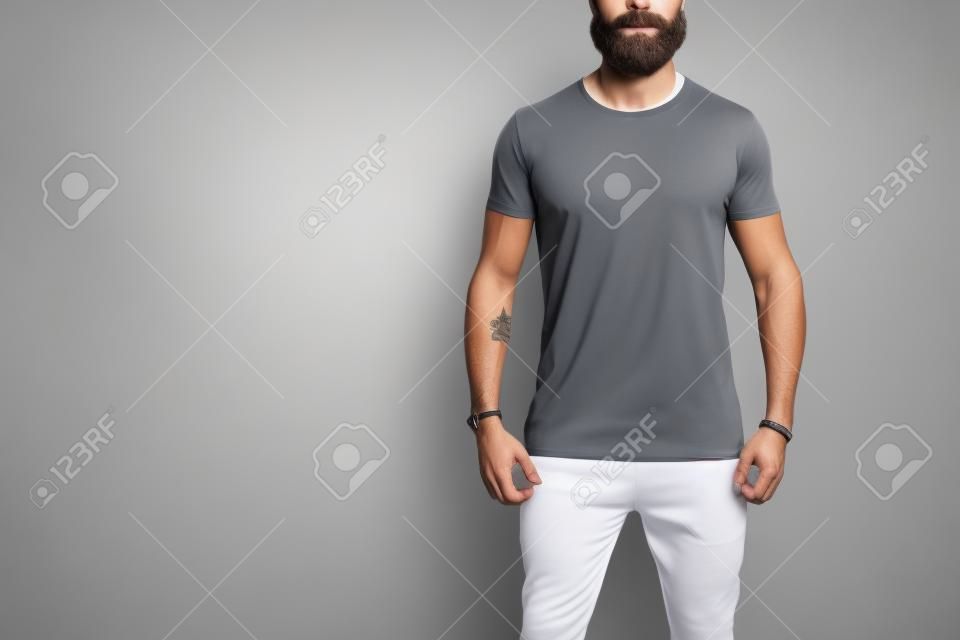 Modello di uomo muscoloso barbuto che indossa una t-shirt bianca vuota con spazio per il tuo logo o design in stile urbano casual su sfondo bianco. Colpo dello studio.