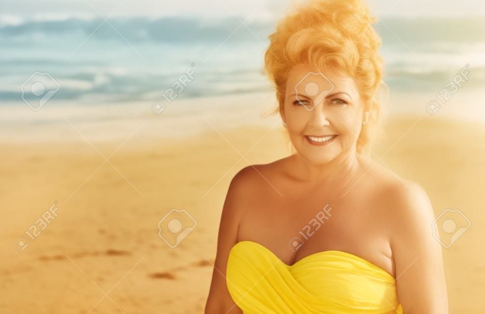 Outdoor Portrait of a Beautiful Mature Woman on the beach wearing a yellow top.