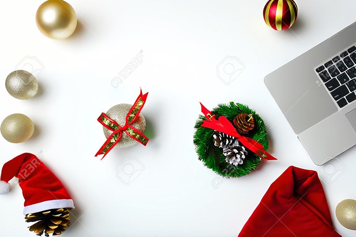 Flat lay top view Christmas office table desk party concept, Christmas workspace with laptop, Santa Claus hat and Christmas decorations on white background