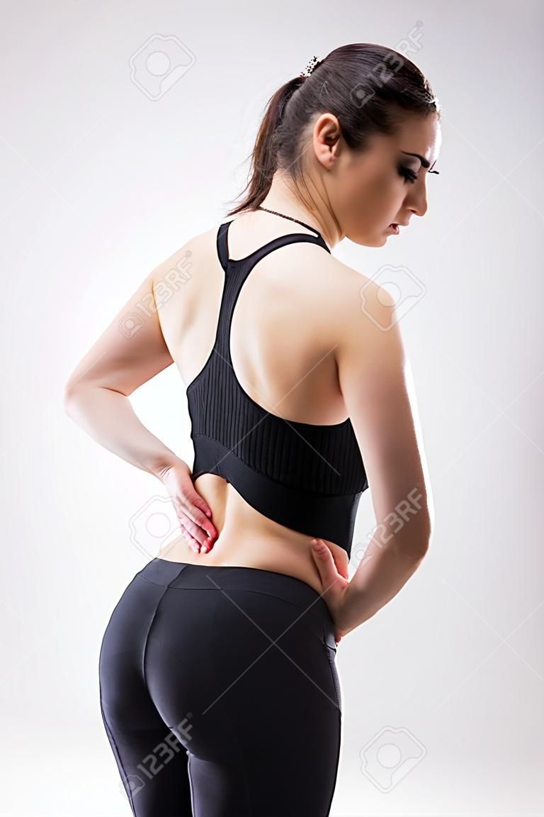 Rear view of young woman with spinal pain. Isolated on white