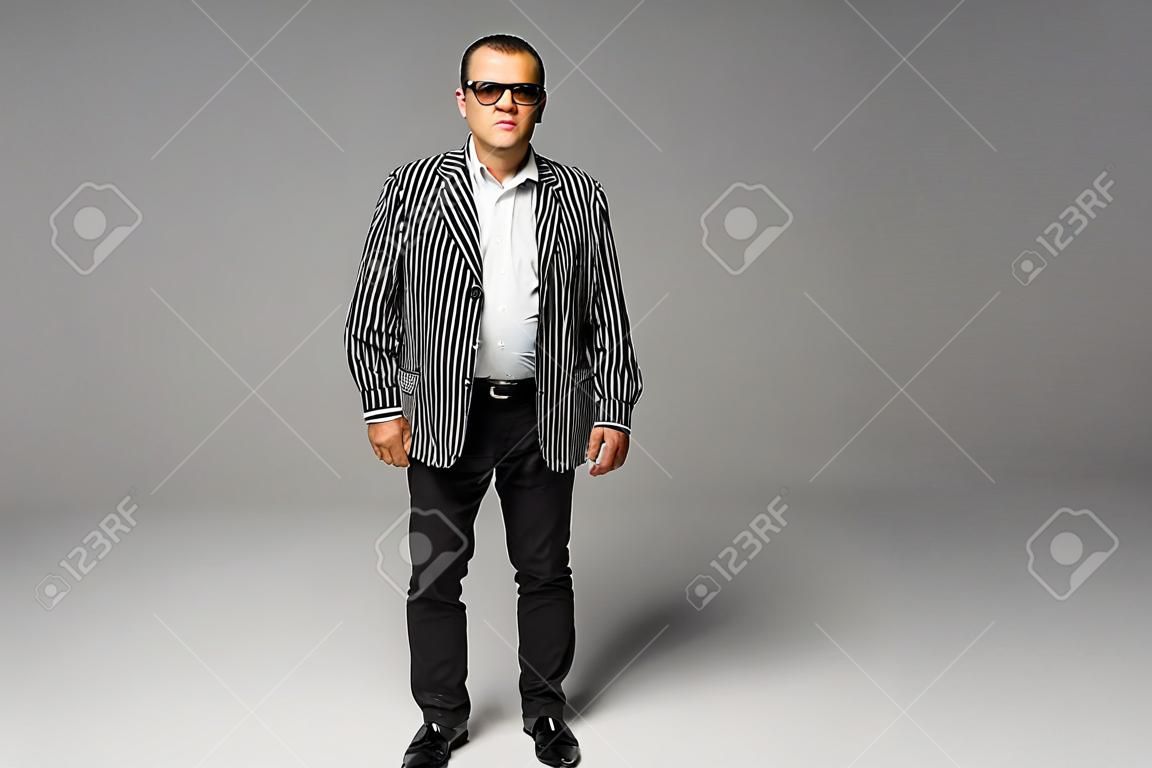 Portrait of a senior older business man standing wearing dark sunglasses on white background