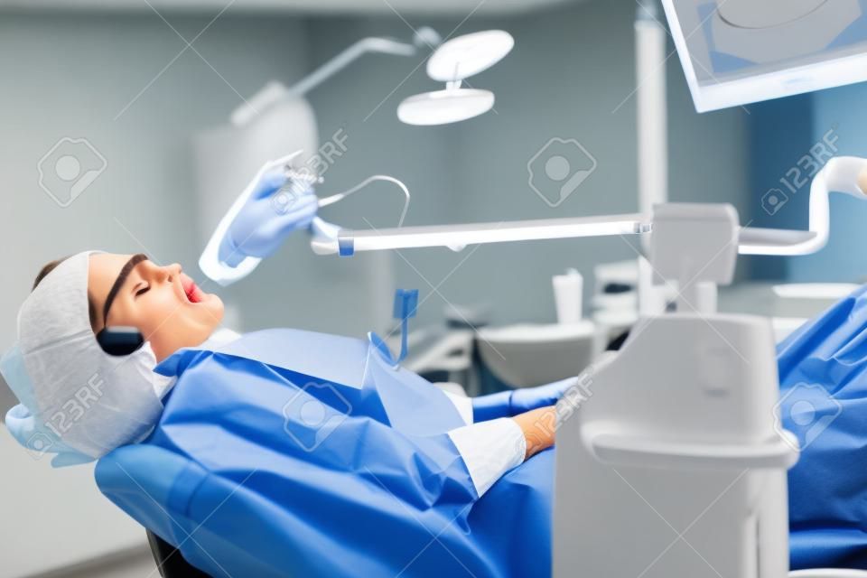 Ritratto di giovane donna che visita l'ufficio del dentista per lo sbiancamento dei denti con il fotopolimero