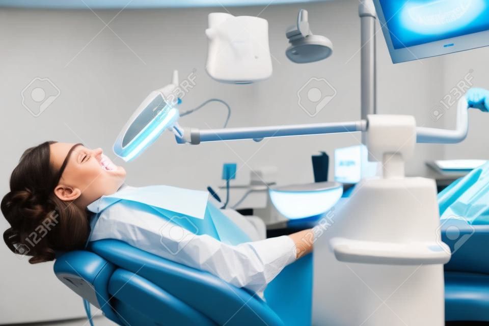Portret van jonge vrouw bezoeken tandarts kantoor voor het bleken van tanden met fotopolymeer