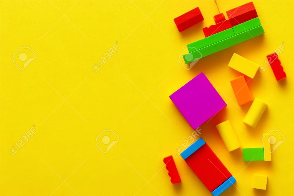 Kids toy constructor details scattered on yellow background