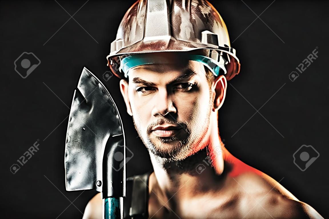 Man with confident face expression isolated on black background. Construction, work and mining concept. Builder or miner wears protective helmet holds shovel. Copy space in upper corner.