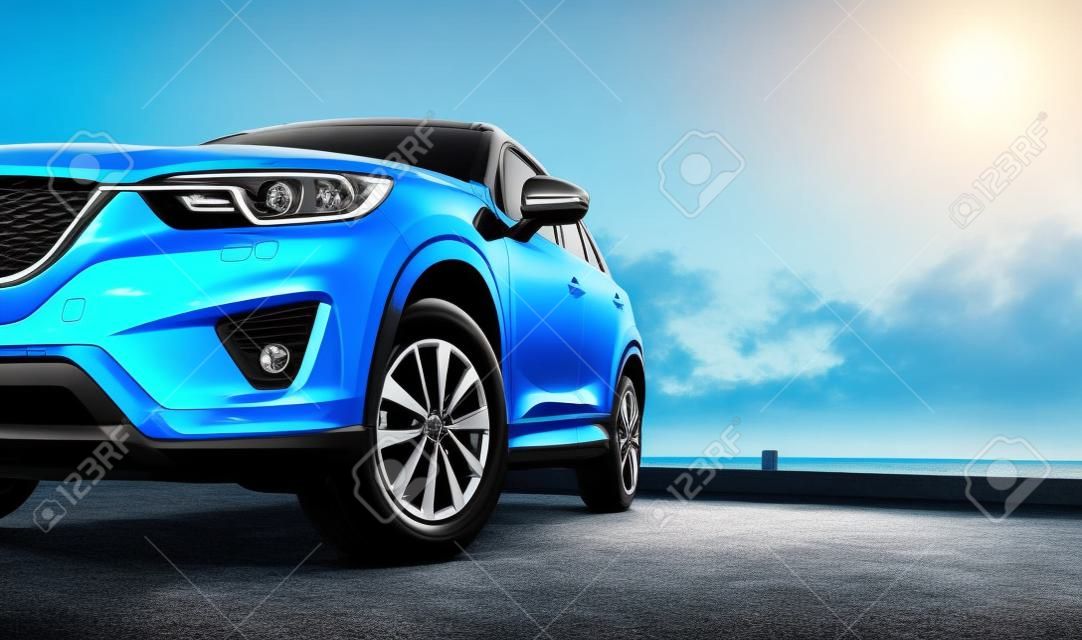 Voiture compacte bleue de SUV avec le sport et la conception moderne garée sur la route concrète par la mer au coucher du soleil. Technologie respectueuse de l'environnement. Concept de succès commercial.