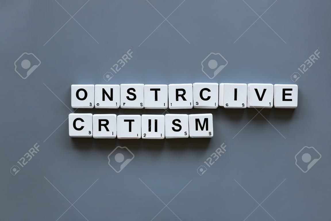 ' Constructief Kritiek'woord gemaakt van vierkante letter woord op grijze achtergrond.