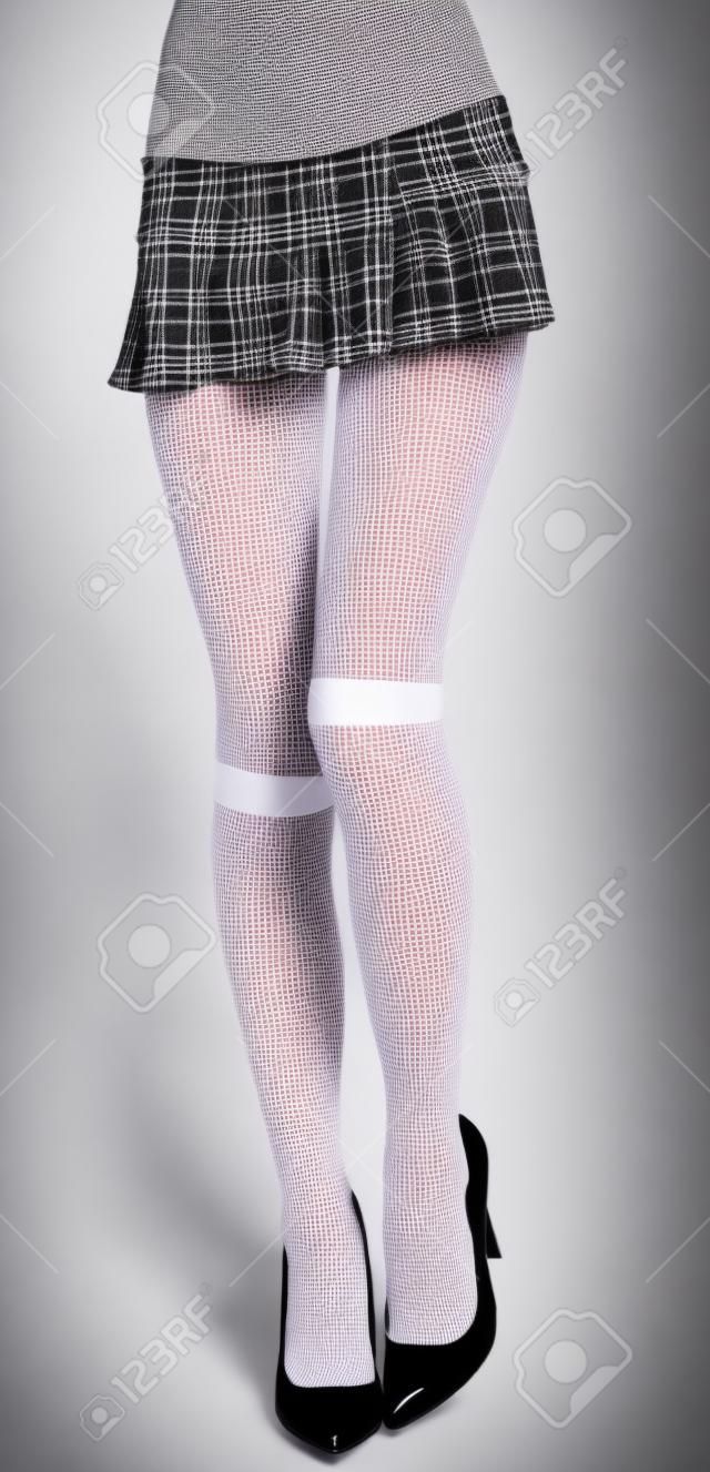 Женщина с ноги в плед юбка школьницы, белые чулки и черные высокие каблуки