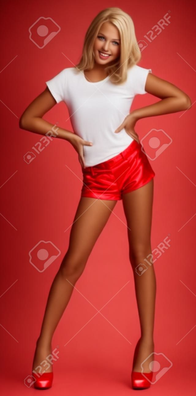Muchacha adolescente rubia en pantalón rojo y tacones