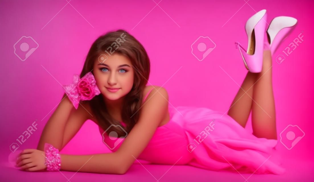 Adolescente hermosa chica posando en un vestido rosa y tacones altos